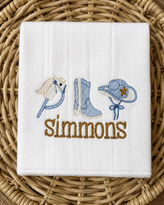 White burp cloth with embroidered hobby horse, cowboy boot and hat and a personalized name