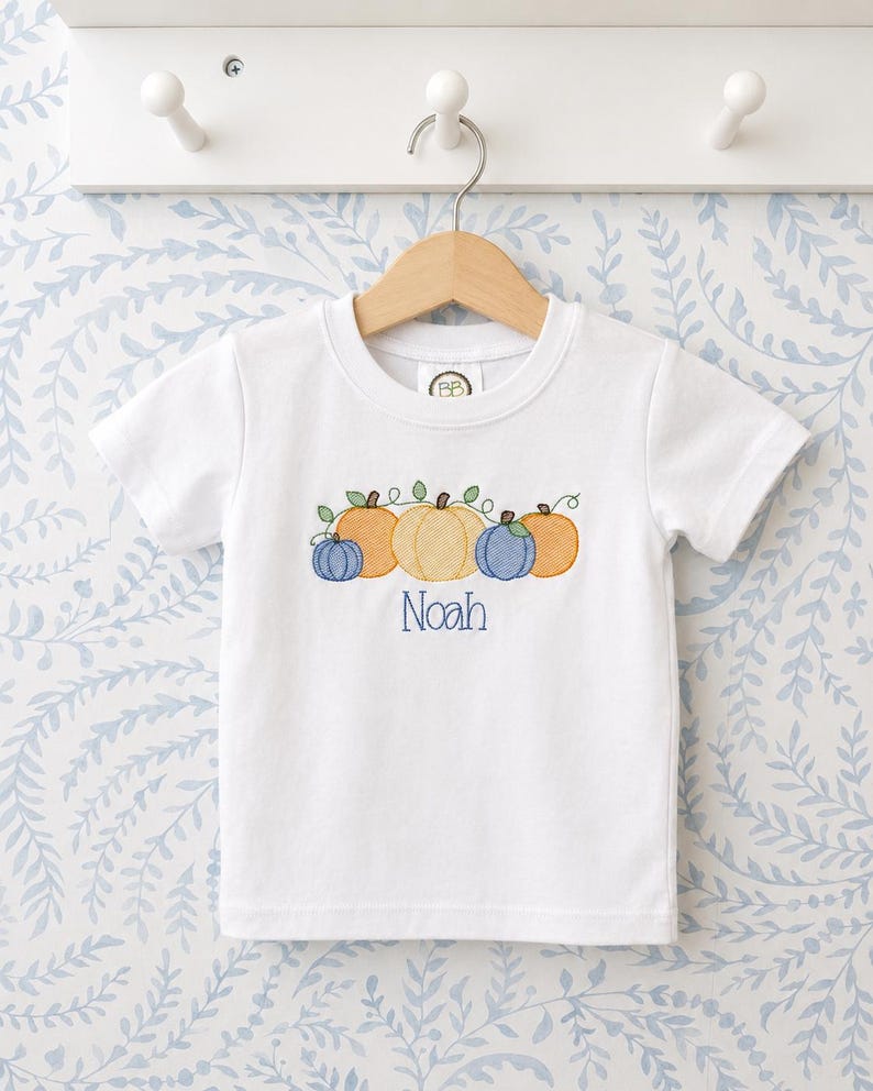 White shirt with four embroidered pumpkins and a personalized name