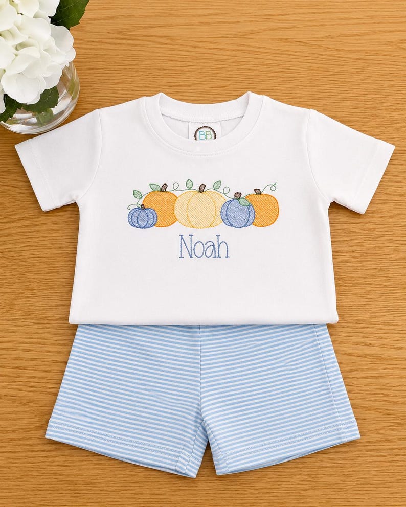 Embroidered pumpkin row with the name Noah in blue, with blue striped shorts
